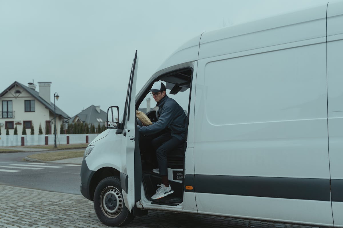 Delivery driver stepping out of a white delivery van