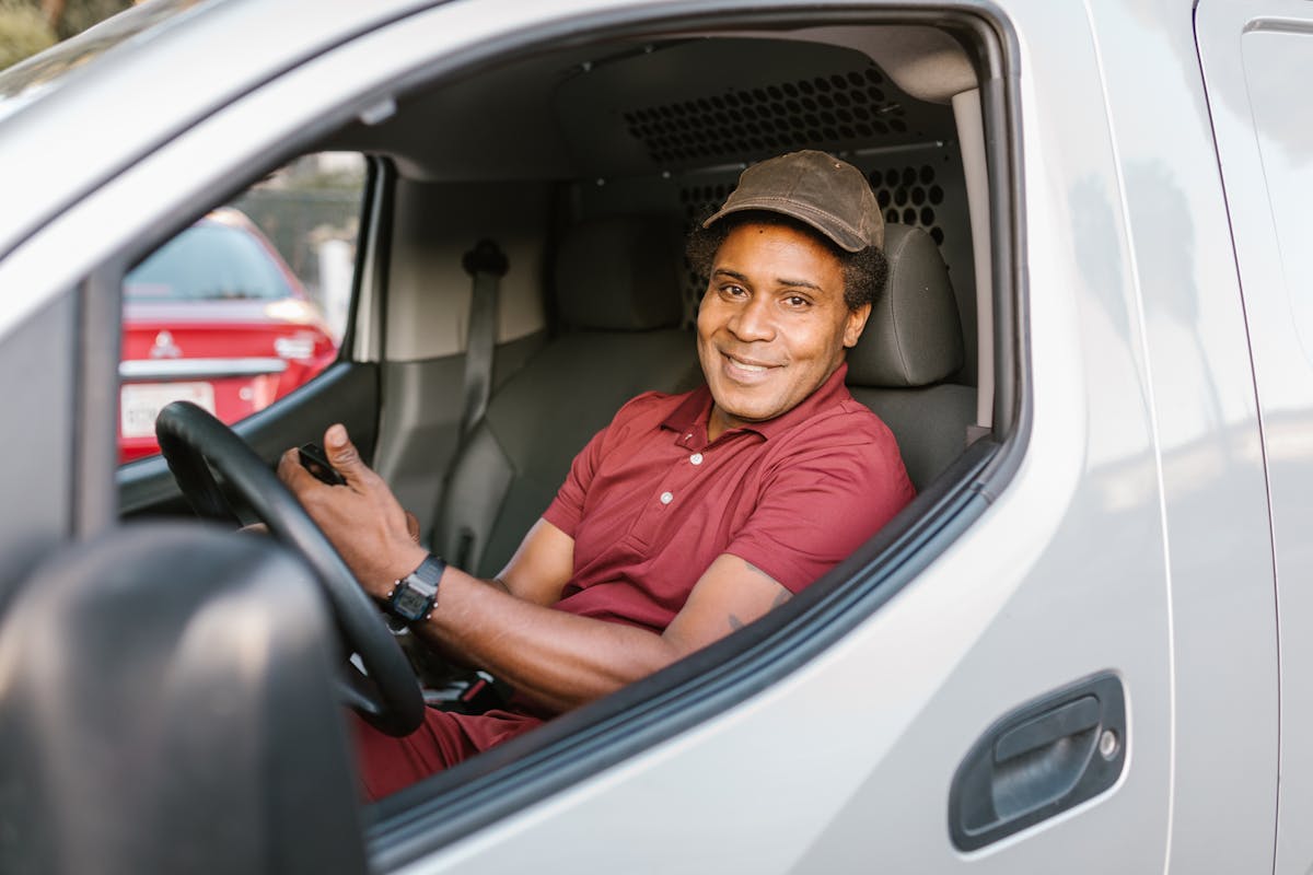 Smiling delivery driver sitting in the drivers seat of a van