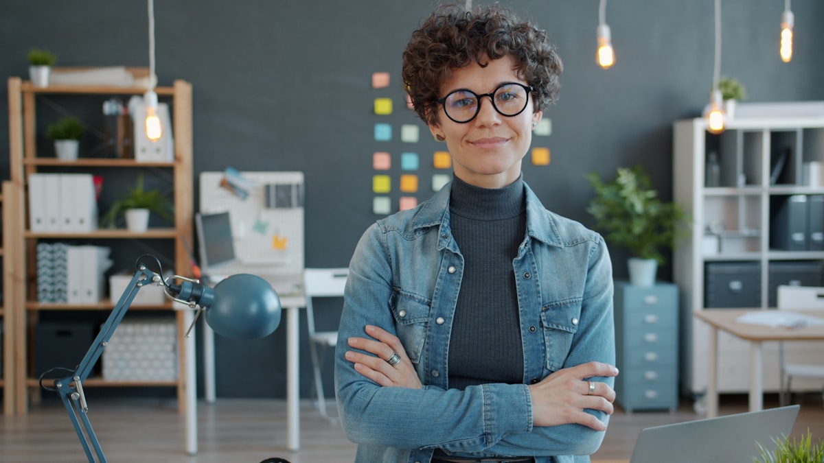 Woman with glasses smiling confidently in office